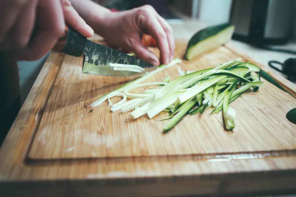 picture displaying a man chopping courgette into strands before frying briefly to be used as an alternative to spaghetti