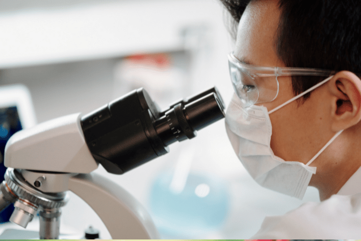 Long COVID virus testing Picture of a scientist looking through a telescope at viruses